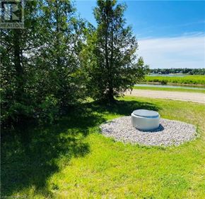 Northern Bruce Peninsula mobile home for rent - A white planter sits in the middle of a gravel circle in a grassy area.