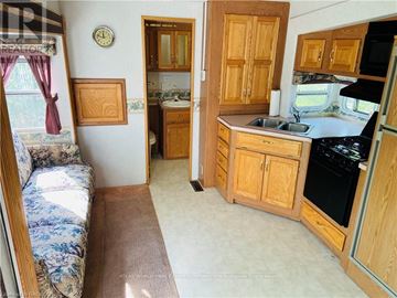 Northern Bruce Peninsula mobile home for rent - A kitchen with wooden cabinets and a stove top oven.