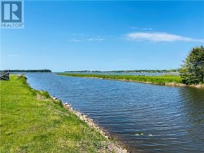 Northern Bruce Peninsula mobile home for rent - A river flows through a grassy area with a clear blue sky above.