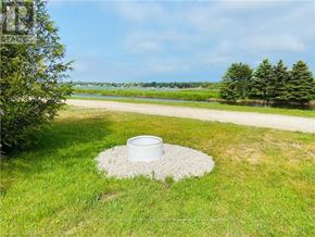 Northern Bruce Peninsula mobile home for rent - A white bucket is placed in a circle of white pebbles on a grassy field.