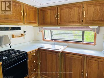Northern Bruce Peninsula mobile home for rent - A kitchen with wooden cabinets and a black stove.