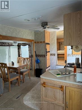 Northern Bruce Peninsula mobile home for rent - A kitchen area with a sink, wooden chairs and cabinets.