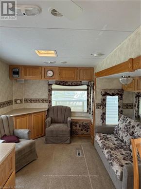 Northern Bruce Peninsula mobile home for rent - A living room with a couch, chair, and a clock on the wall.