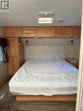 Northern Bruce Peninsula mobile home for rent - A bedroom with a bed, wooden cabinets, and a window.
