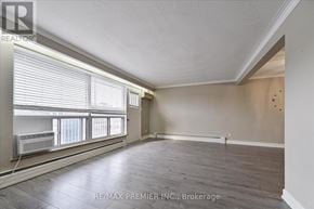 Toronto (Bathurst Manor) triplex for rent - A spacious room with wooden floors and a window with blinds.