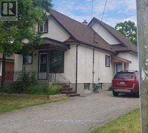 Niagara Falls (Clifton Hill) house for rent - A red car is parked in front of a white house with a brown roof.