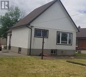 Niagara Falls (Clifton Hill) house for rent - A small white house with a brown roof and a sign that says REALTOR.