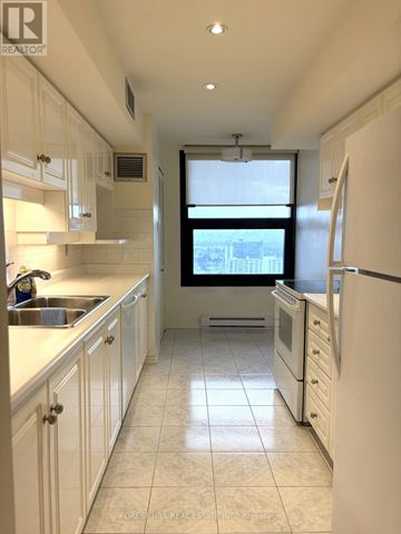 Mississauga (Applewood) condo for rent - A kitchen with white cabinets and a window overlooking the city.