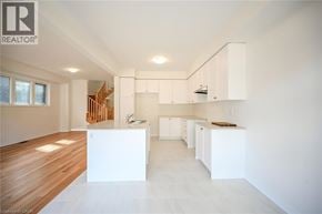 Hamilton house for rent - A spacious, white kitchen with wooden floors and a staircase in the background.