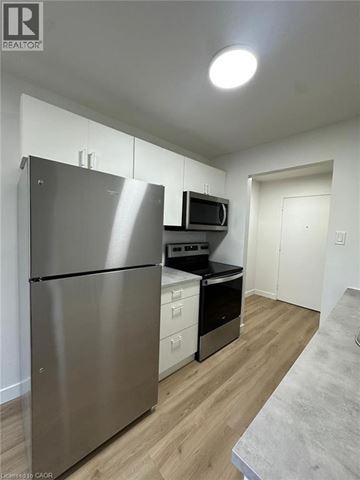 Waterloo apartment for rent - A stainless steel refrigerator is in a kitchen with wood floors and white walls.