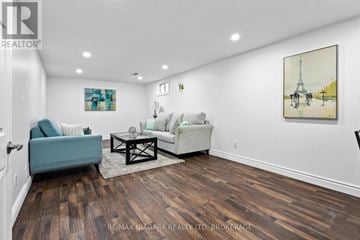 Niagara Falls (Ascot) house for rent - A living room with a blue couch, a white couch, and a painting of the Eiffel Tower on the wall.