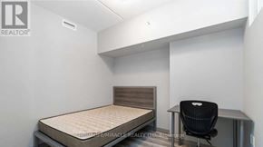 Waterloo condo for rent - A bedroom with a bed, chair, and a brochure on the wall.