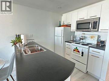 Vancouver apartment for rent - A kitchen with white cabinets and a black countertop.
