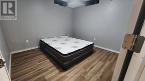 Niagara Falls (Brown) house for rent - A bed with a white mattress and a black frame is in a room with wooden flooring.
