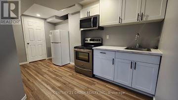 Niagara Falls (Brown) house for rent - A kitchen with white cabinets and a wooden floor.