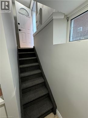 Brantford house for rent - A staircase with a black carpeted runner and white walls.