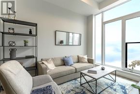 Oshawa (O'neill) condo for rent - A living room with a couch, chair, and a table with a vase of flowers on it.