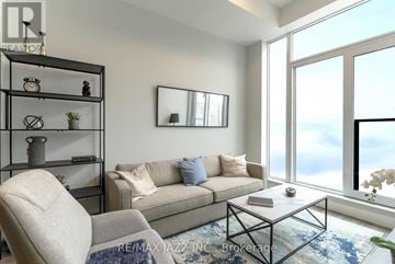 Oshawa (O'neill) condo for rent - A living room with a couch, chair, and a table with a vase of flowers on it.