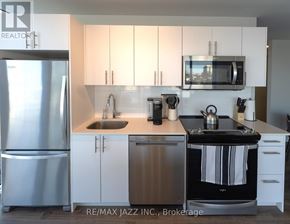 Oshawa (O'neill) condo for rent - A kitchen with white cabinets and a stainless steel refrigerator.