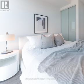 Oshawa (O'neill) condo for rent - A bedroom with a white bed and a grey blanket.
