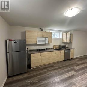 Ottawa triplex for rent - A kitchen with a refrigerator, microwave, oven, and cabinets.
