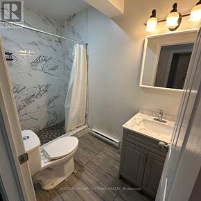 Ottawa triplex for rent - A bathroom with a marble shower and a white toilet.