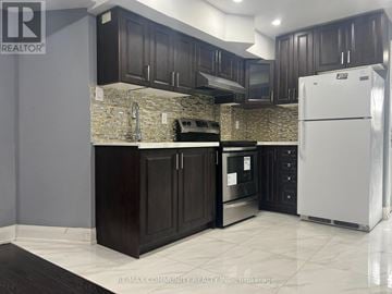 Ajax (Northwest Ajax) multi-family for rent - A kitchen with a white refrigerator and dark brown cabinets.