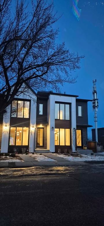Calgary apartment for rent - A house with a lit up front porch and a tree in the front yard.