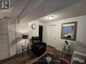 Toronto (Malvern) house for rent - A living room with a black leather chair and a glass table with a vase of flowers on it.