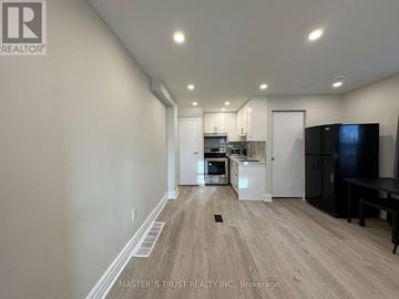 Toronto (Caledonia-Fairbank) house for rent - A kitchen with white cabinets and a black fridge is shown in this image.