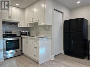 Toronto (Caledonia-Fairbank) house for rent - A kitchen with white cabinets and a black refrigerator.