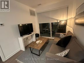 Gravenhurst (Muskoka (S)) condo for rent - A living room with a grey couch, a wooden coffee table, and a flat screen TV mounted on the wall.