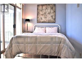 Richmond apartment for rent - A bed with a white frame and a white comforter with a pattern on it.