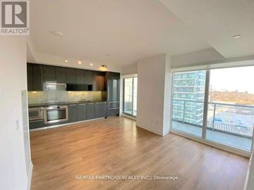 Toronto (Bayview Village) condo for rent - A spacious living room with hardwood floors and a large window overlooking a parking lot.