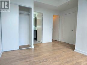 Toronto (Bayview Village) condo for rent - A room with white walls and wooden flooring, with a door on the left and a mirror on the right.