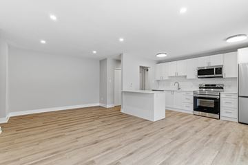 Kitchener apartment for rent - A modern kitchen with white cabinets and a wooden floor.