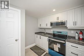 Oakville (Wo West) house for rent - A kitchen with white cabinets and a black stove top oven.