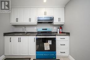 Oakville (Wo West) house for rent - A kitchen with white cabinets and a black countertop.
