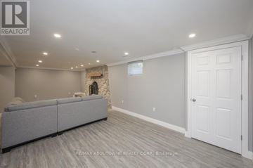 Oakville (Wo West) house for rent - A spacious living room with a grey sofa and a stone fireplace.