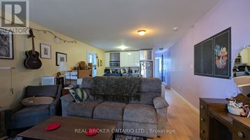 Toronto (Danforth Village-East York) other for rent - A living room with a grey couch and a guitar hanging on the wall.