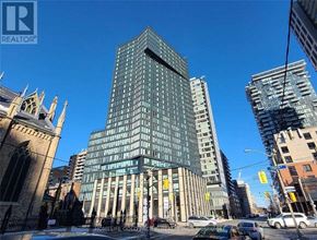 Toronto (Church-Yonge Corridor) condo for rent - A tall building with many windows is in the middle of a city street.