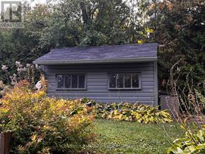 Collingwood house for rent - A small house with a grey roof surrounded by greenery and trees.