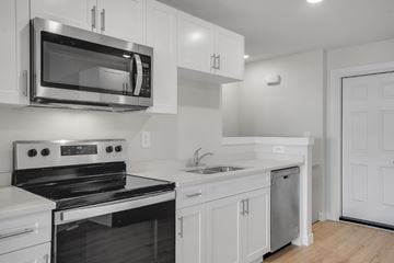 Saskatoon apartment for rent - A modern kitchen with white cabinets and stainless steel appliances.