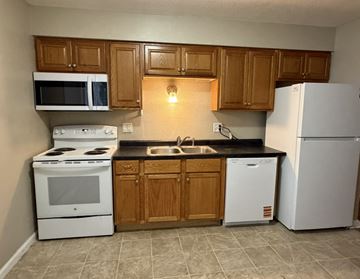 Grinnell apartment for rent - A kitchen with white appliances and wooden cabinets.