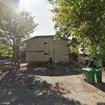 Seattle apartment for rent - A street view of a building with a green trash bin in front.