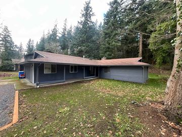 Bellingham apartment for rent - A house with a grey roof and a grey garage door is surrounded by trees.