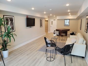 Metuchen apartment for rent - A living room with a white couch, a black chair, and a television on the wall.