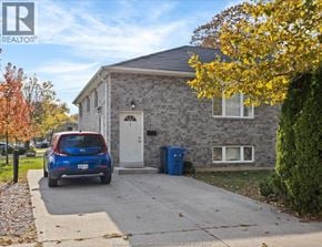Windsor fourplex for rent - A blue car is parked in front of a grey house.