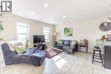 Windsor fourplex for rent - A living room with a grey couch and a black chair.