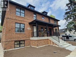 Windsor triplex for rent - A red brick house with a black metal railing on the porch.